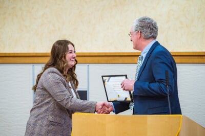 Sydney Lurvey shaking hands and receiving a certificate.