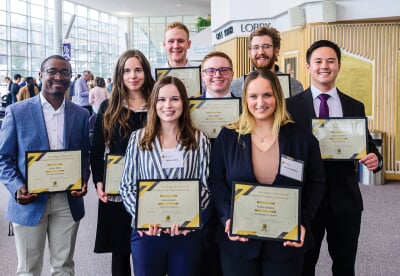 Eight students holding their certificates at the awards ceremony.