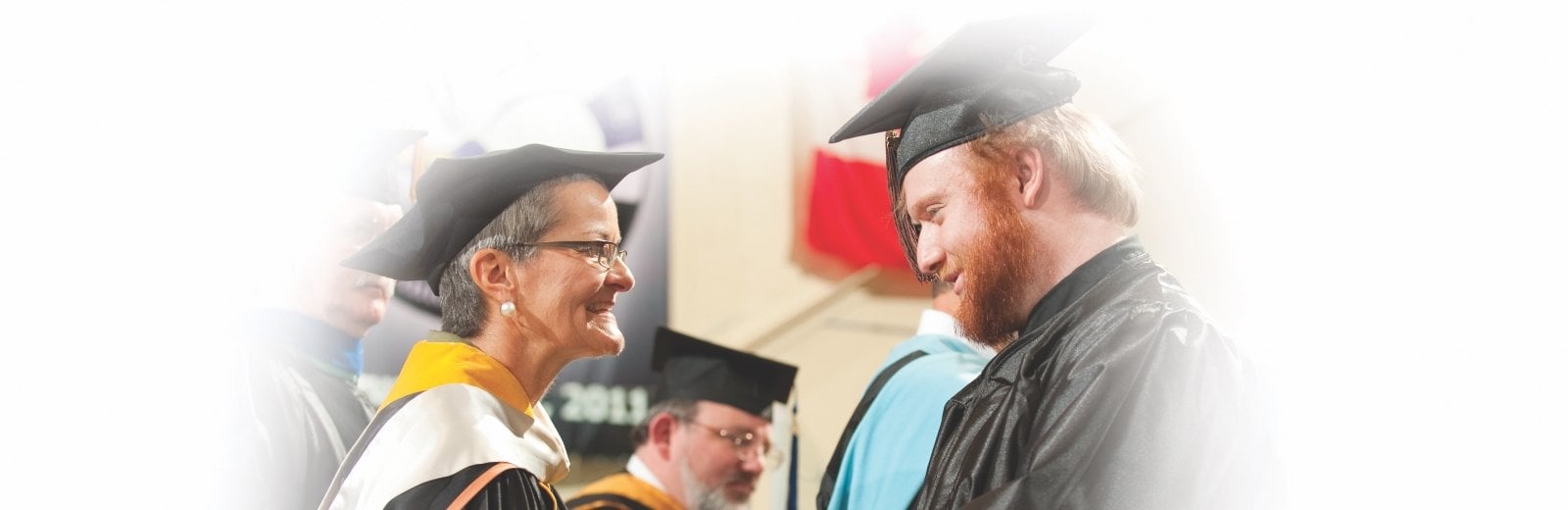 Board member hands a diploma to a graduate.