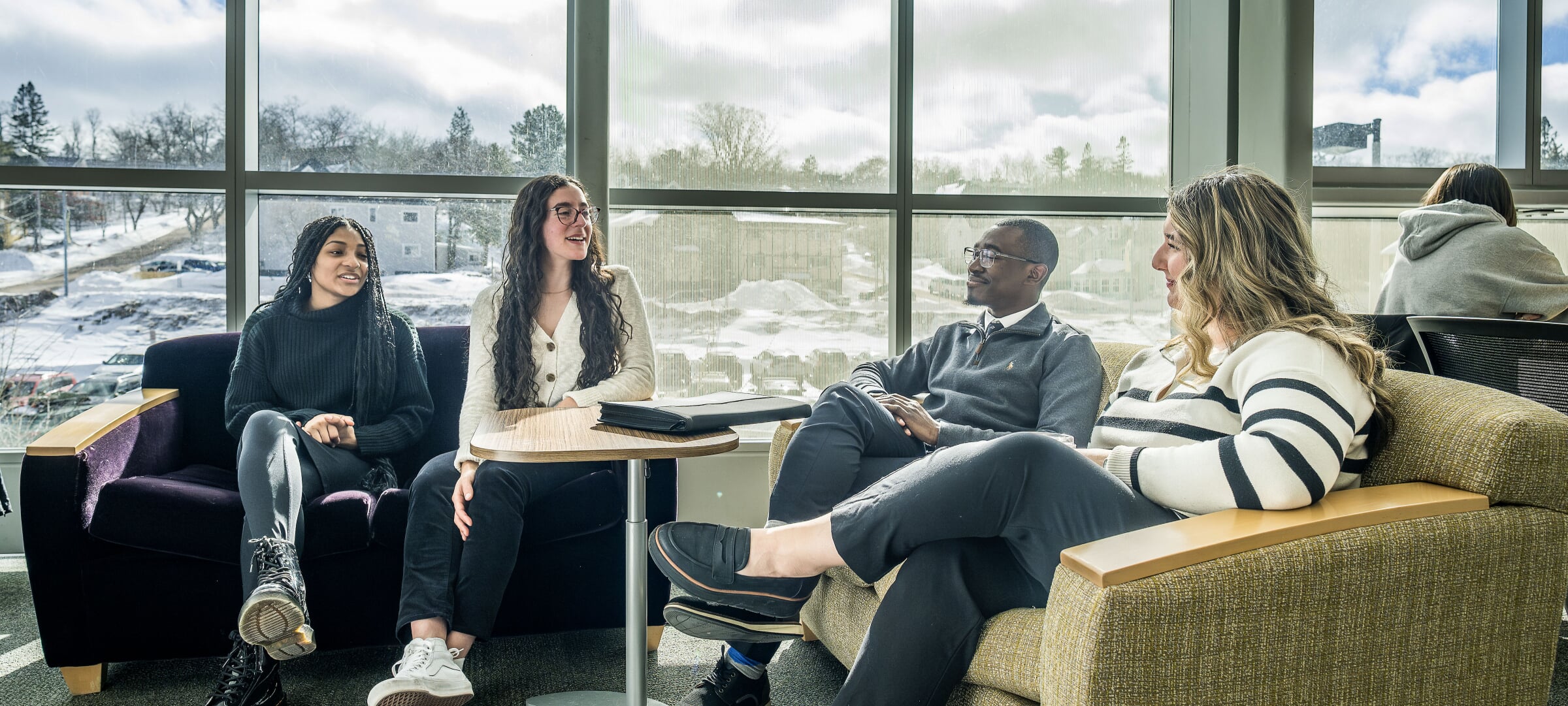 Two students sitting with a faculty member outside.