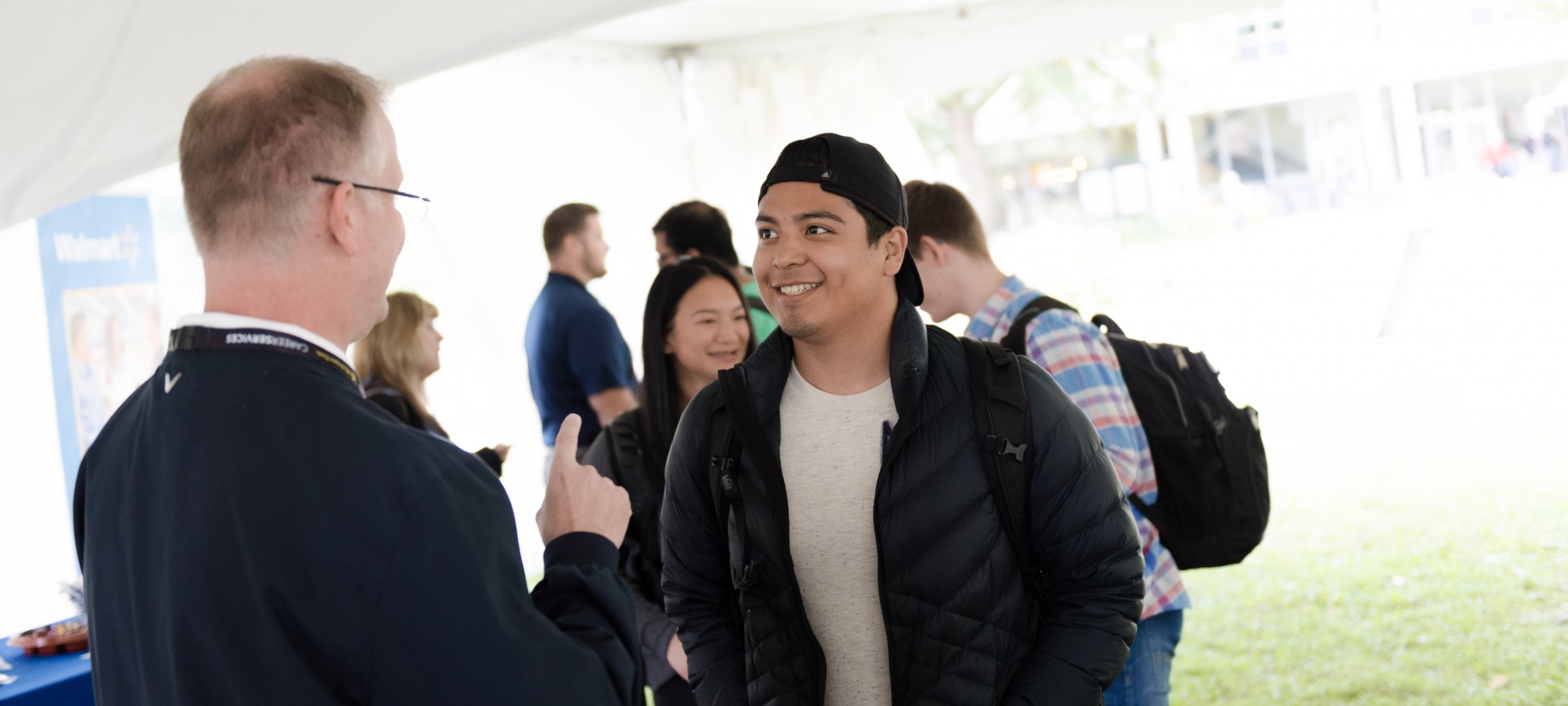 Student smiling at recruiter outside on campus