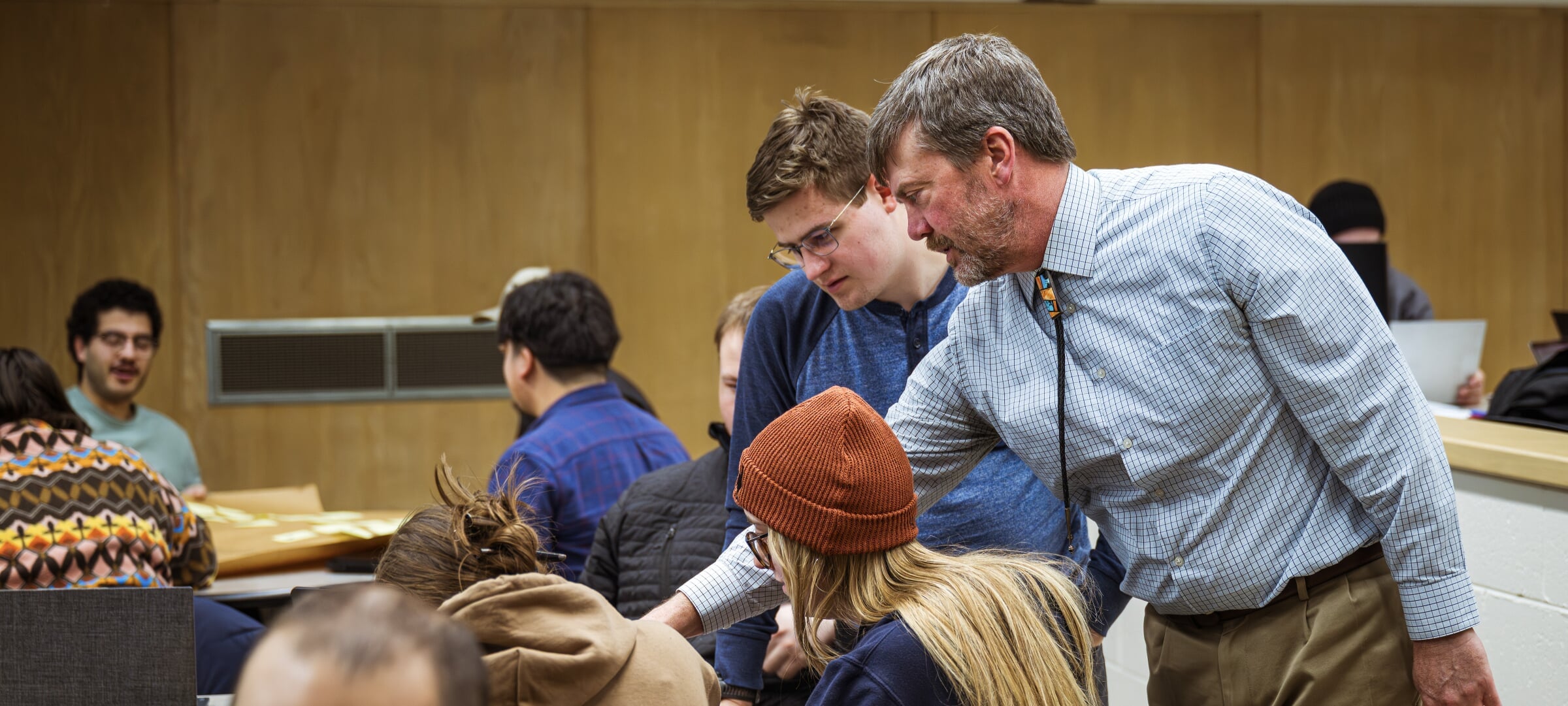 Professor works with two students in a classroom