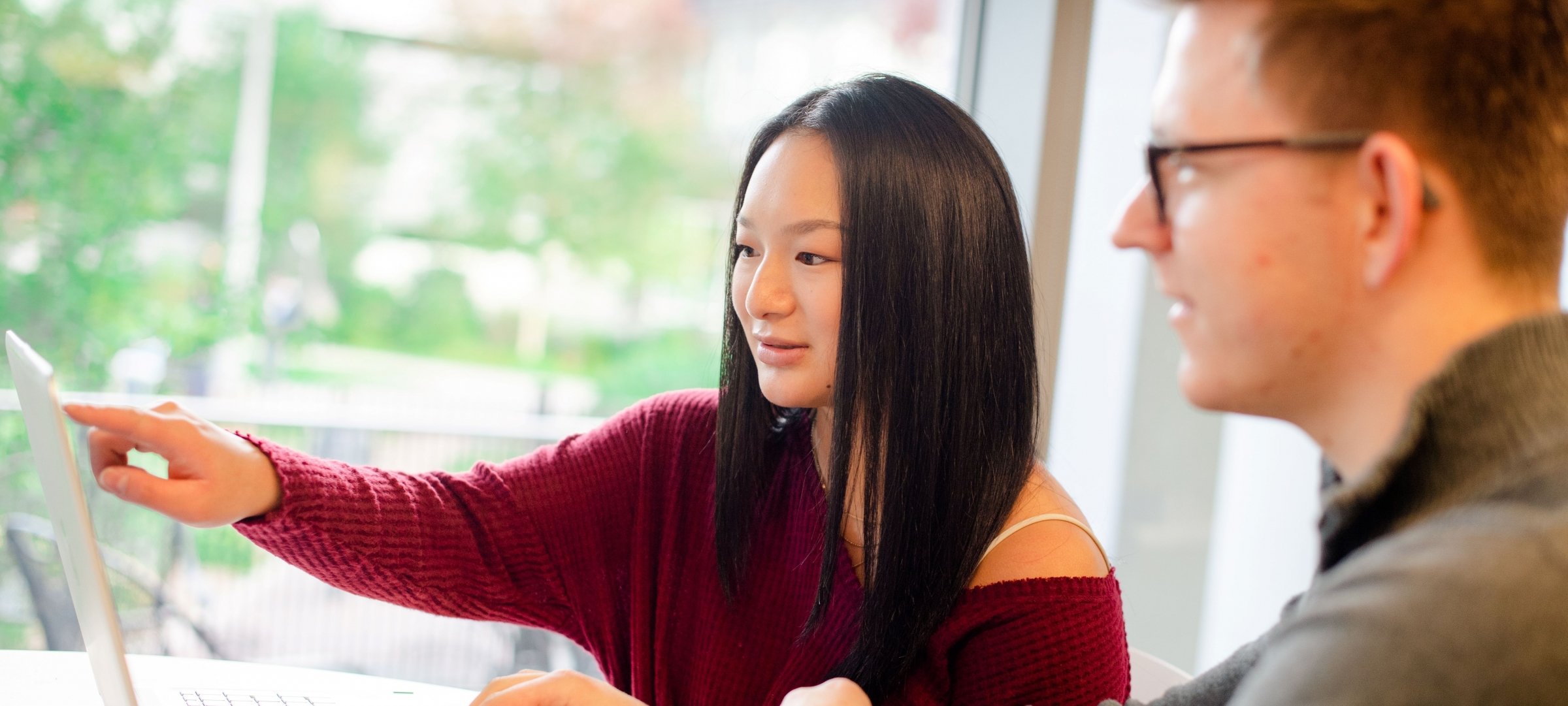 Student pointing to a laptop screen.