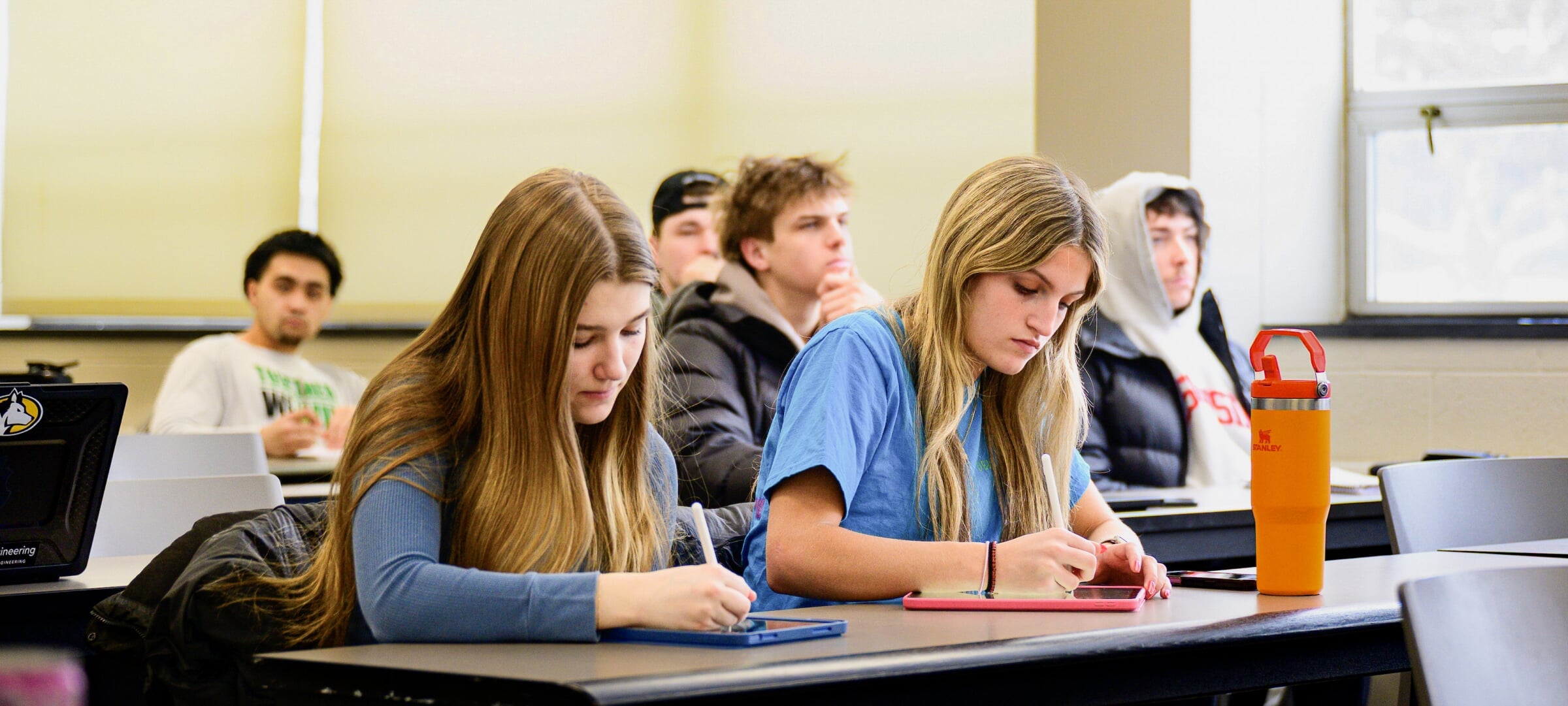 Two students take notes during a classroom session
