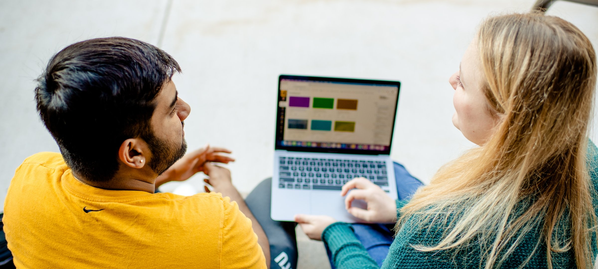 Two students working over a laptop