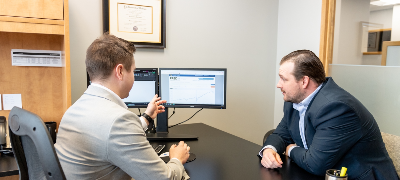 Two business professionals in an office looking at a computer screen.