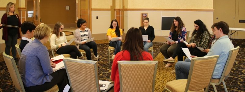Thirteen students sitting in a circle participating in a group workshop