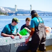 Students placing concrete canoe in canal