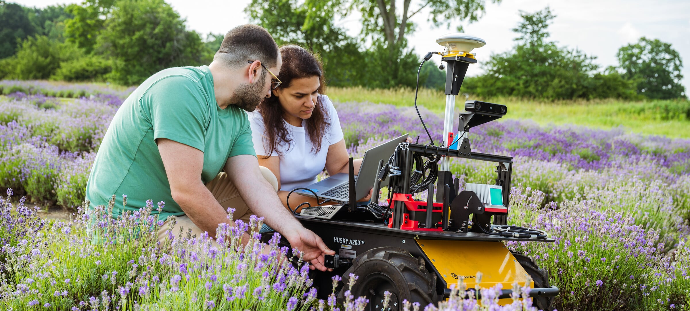 Two students working on a robot in a lavender field
