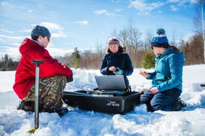 students in the snow with a laptop