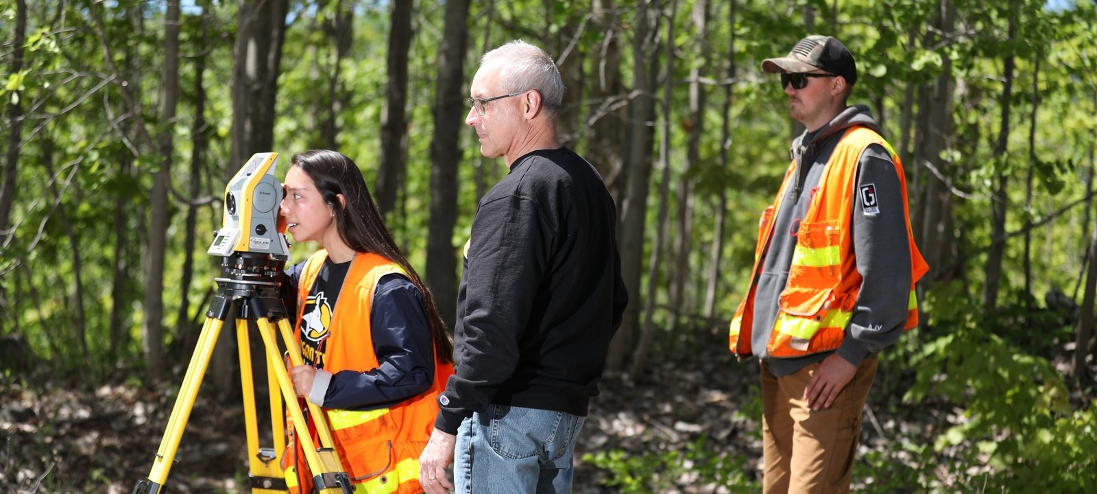 Faculty teaching students to use surveying equipment.