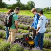 Four students in a field looking at a robot