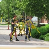 Two students holding surveying equipment