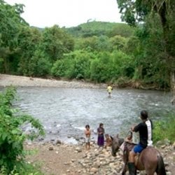 People near a river with one person on horseback.