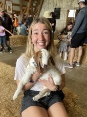  Olivia Capelle, smiling and holding a baby goat.