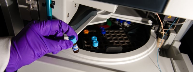 Researcher placing vial in machine.