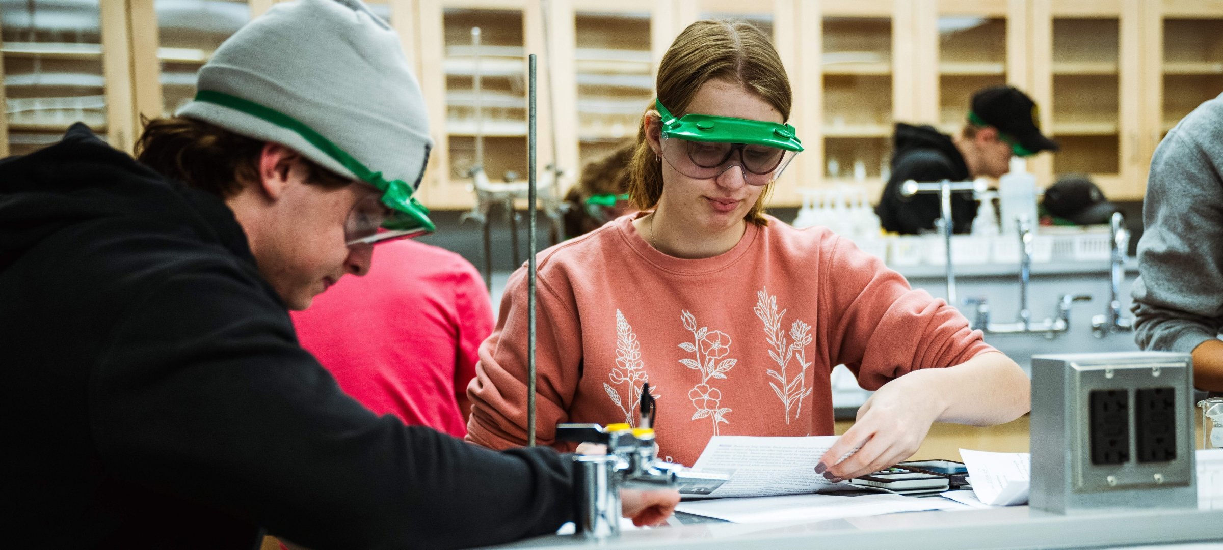 Male and female student working individually on lab report in teaching lab