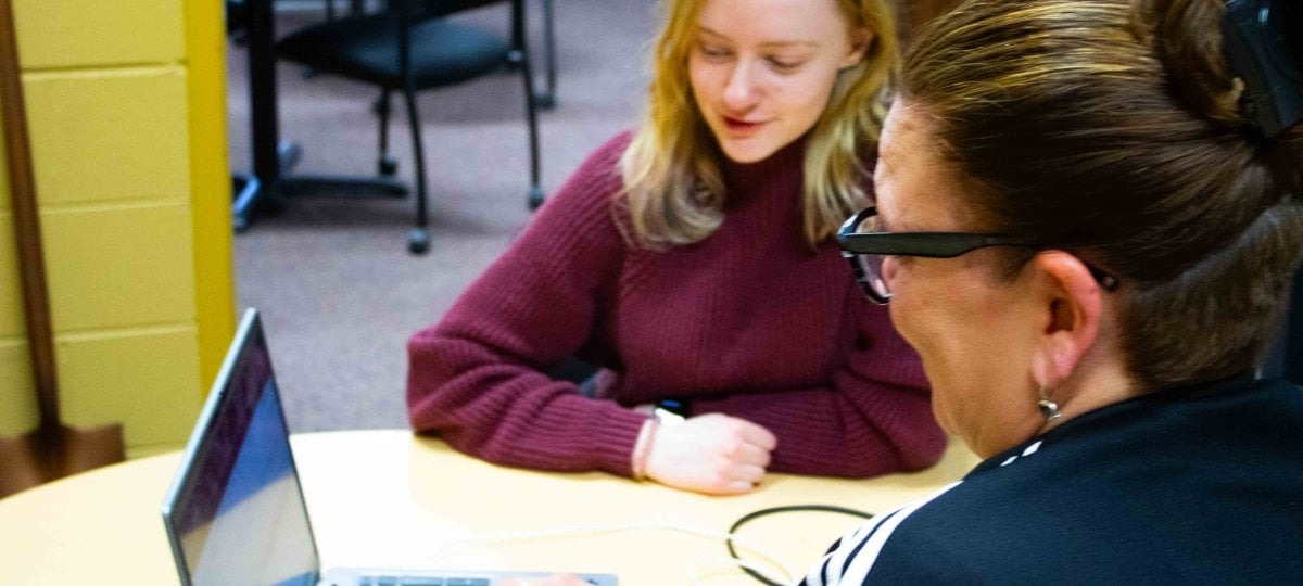 A student being advised by an advisor with both looking at a laptop screen