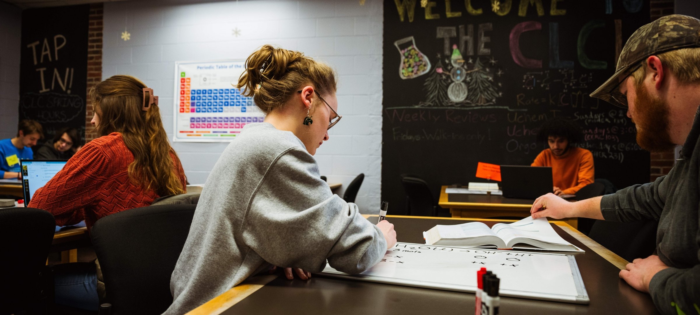 Female student working with male in Chemistry Learning Center. Darker image