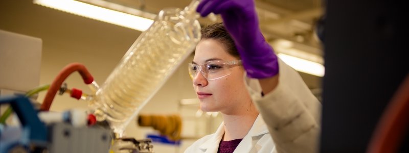 A person in a lab coat using chemistry equipment.