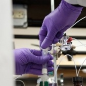 A person mixing something in a beaker in a lab