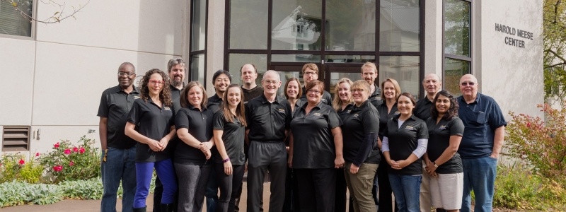 19 faculty and staff standing outside the Harold Meese Center
