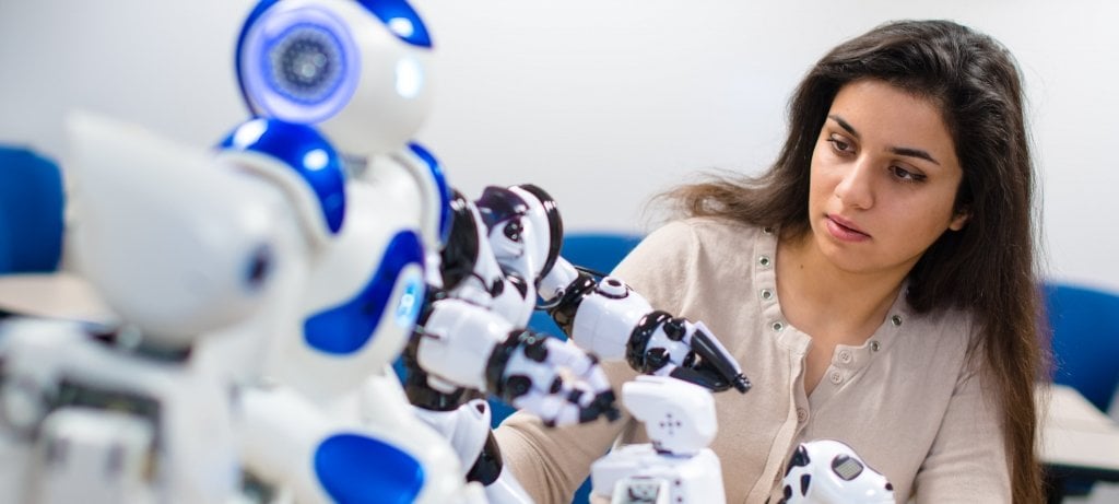 Student sitting and observing robots as they move.