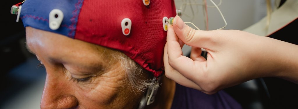 Researchers connect an EEG machine to a participant. 
