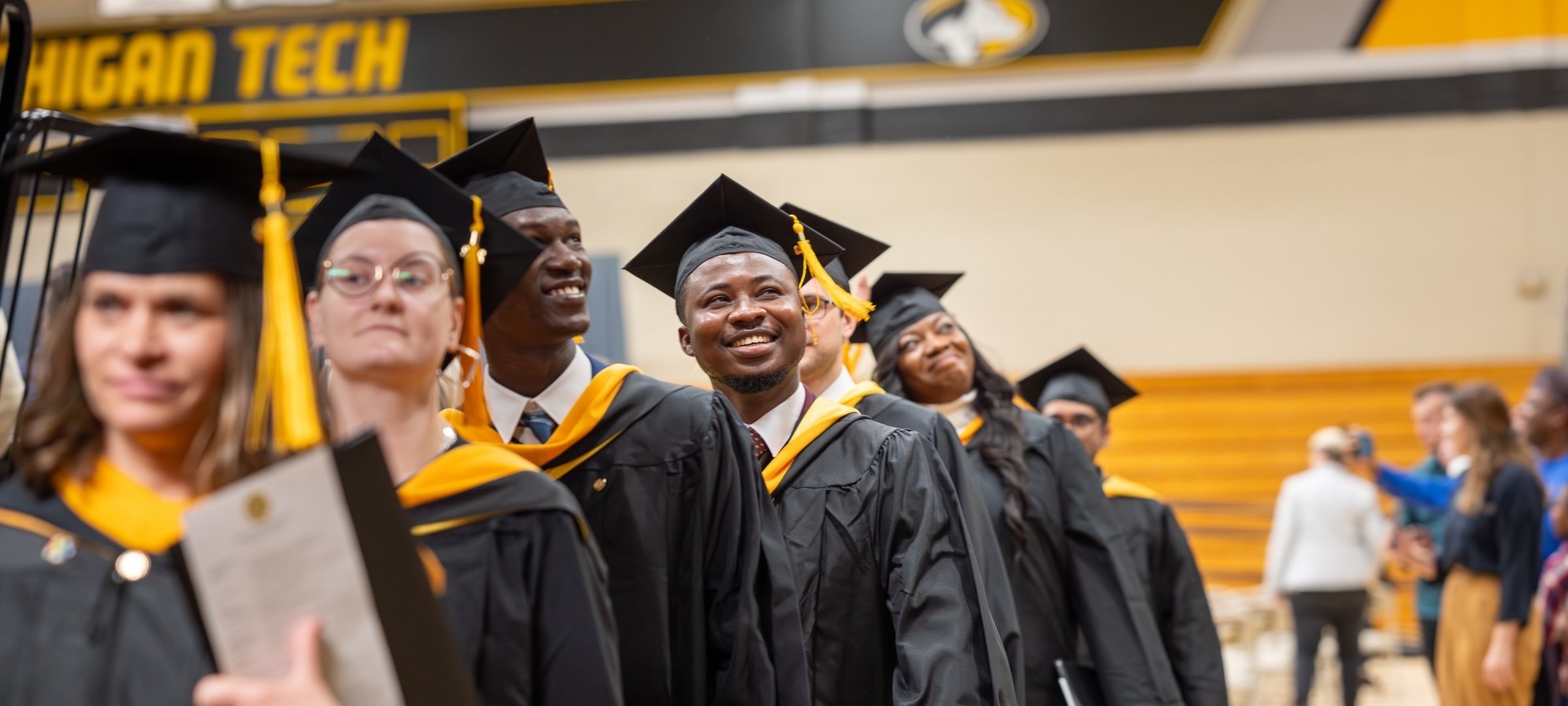 Students lined up walking at Commencement smiling.