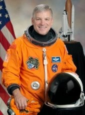 Col. Gregory H. Johnson, wearing an orange spacesuit.