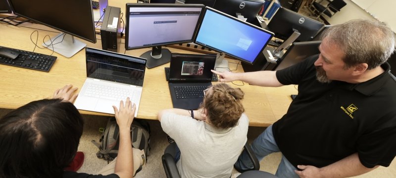 Faculty member Todd Arney, Applied Computing, with CNSA students in the lab