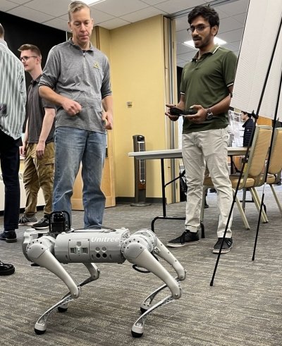 Electrical engineering grad student Shivayogi Akki (right), presents his research on “Benchmarking Model Predictive Control and Reinforcement Learning for Legged Robot Locomotion” at Showcase[AI]. On the left is Keith Vertanen, computer science faculty member.