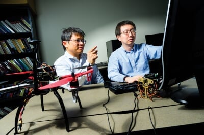 Bo Chen and Niusen Chen working together at a computer with a drone on the desk.