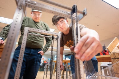 Students working on gears on the frame of the robot.