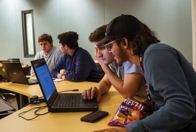 Two groups of two students working at laptops.