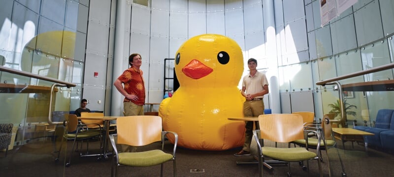 Two faculty members standing next to a giant blown-up rubber ducky.