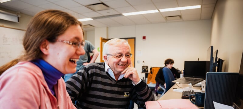 Soner Onder and a student smiling at a computer screen in a computer lab.