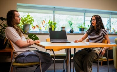 Students Tyson Watson and Diana Shadibaeva sitting at a table with a laptop in the middle.