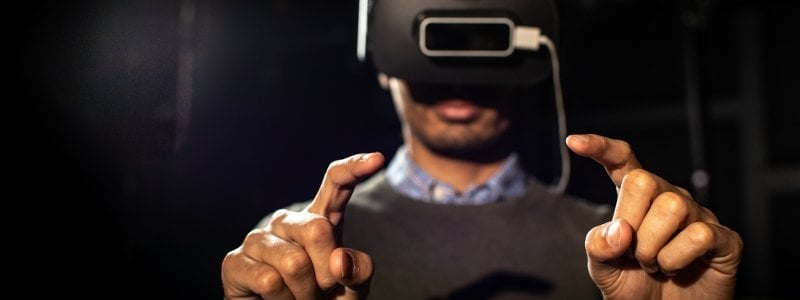 Doctoral student, Jiban Adhikary, using VR headset with index fingers pointed.