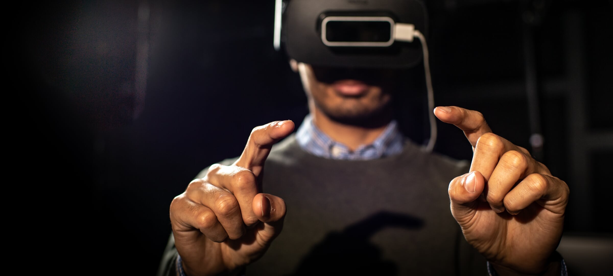 Doctoral student, Jiban Adhikary, using VR headset with index fingers pointed.