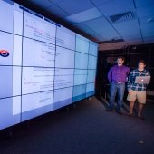Two researchers standing next to a large screen