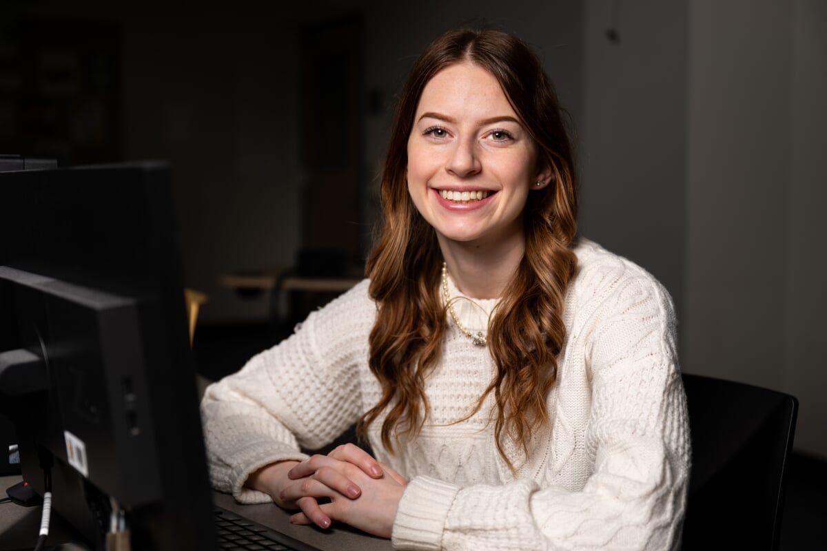 A Michigan Tech computer science student sits at her laptop smiling