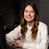 A Michigan Tech computer science student sits at her laptop smiling
