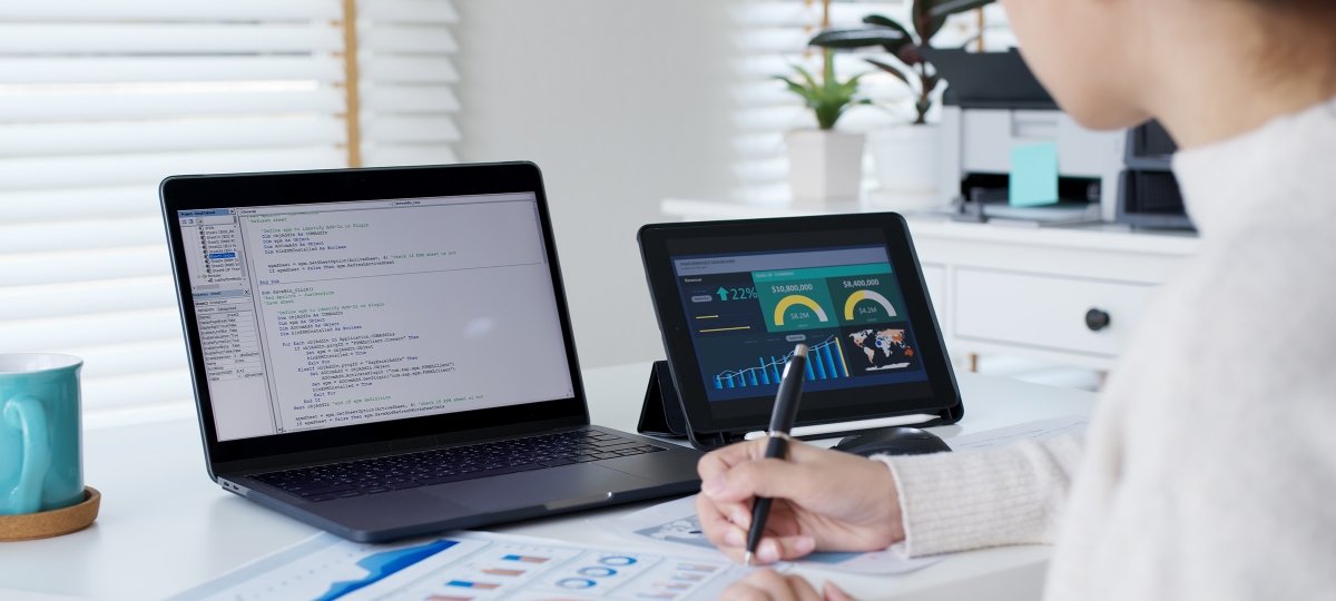 A student with two laptops, paper, pen