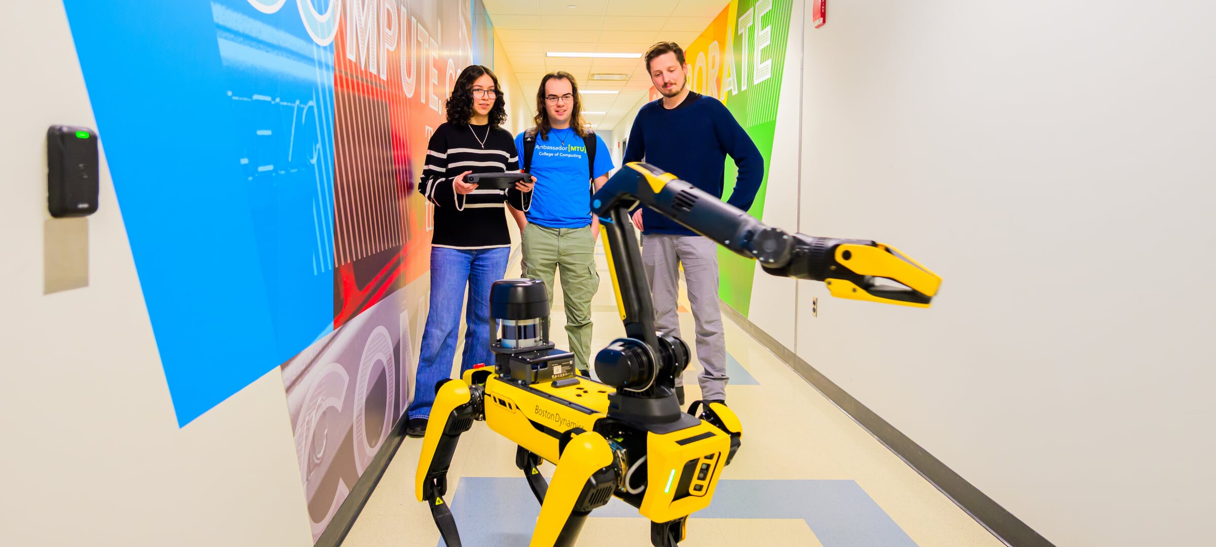 Three students work with Balto the robot dog