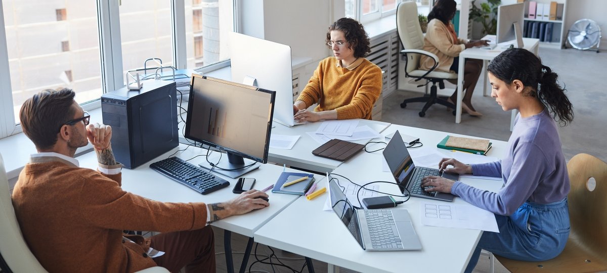 Three students study together with computers and notebooks
