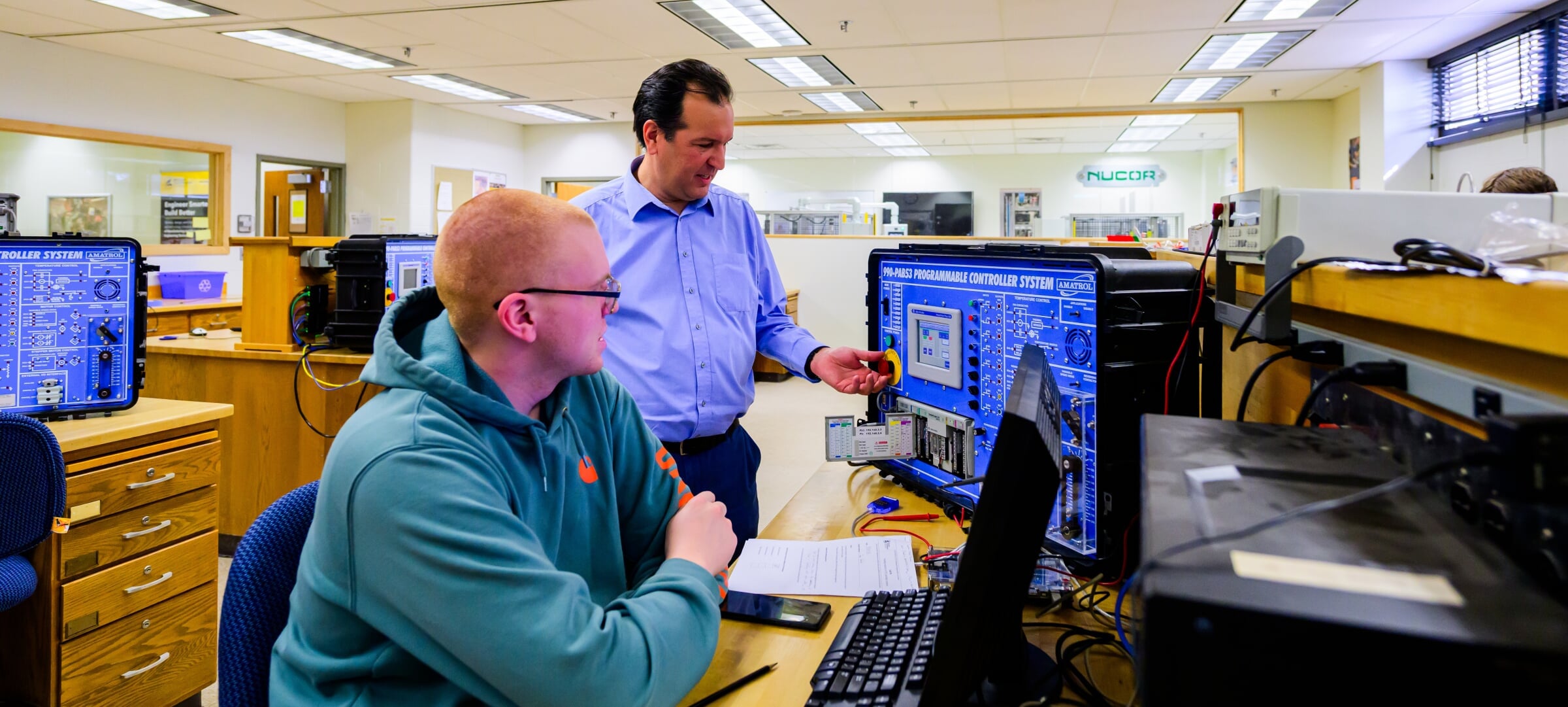 Student working and faculty in a computing lab.