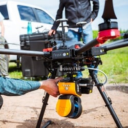 Close view of an aerial drone with sensing equipment attached, sitting on the ground.