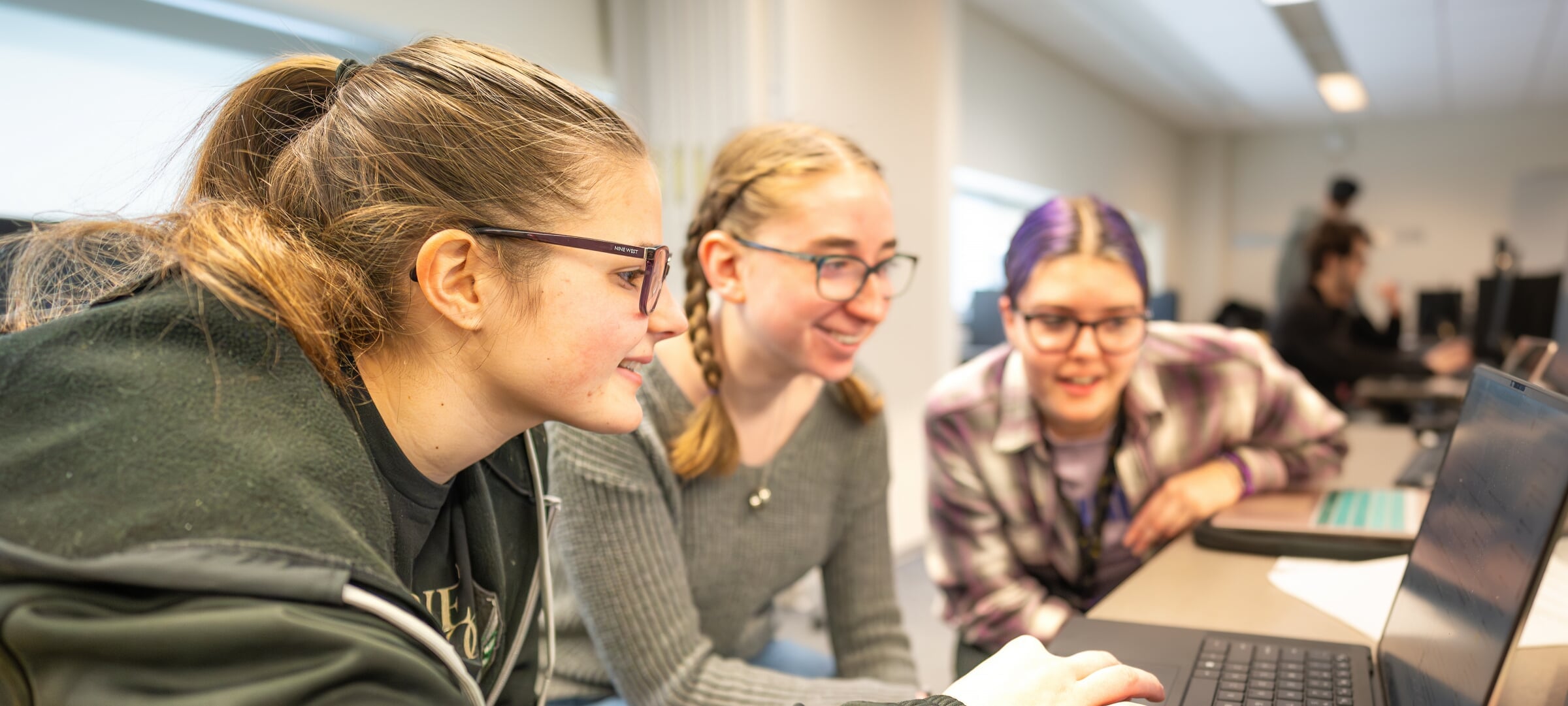 Three female students smiling in acknowledgement of positive results
