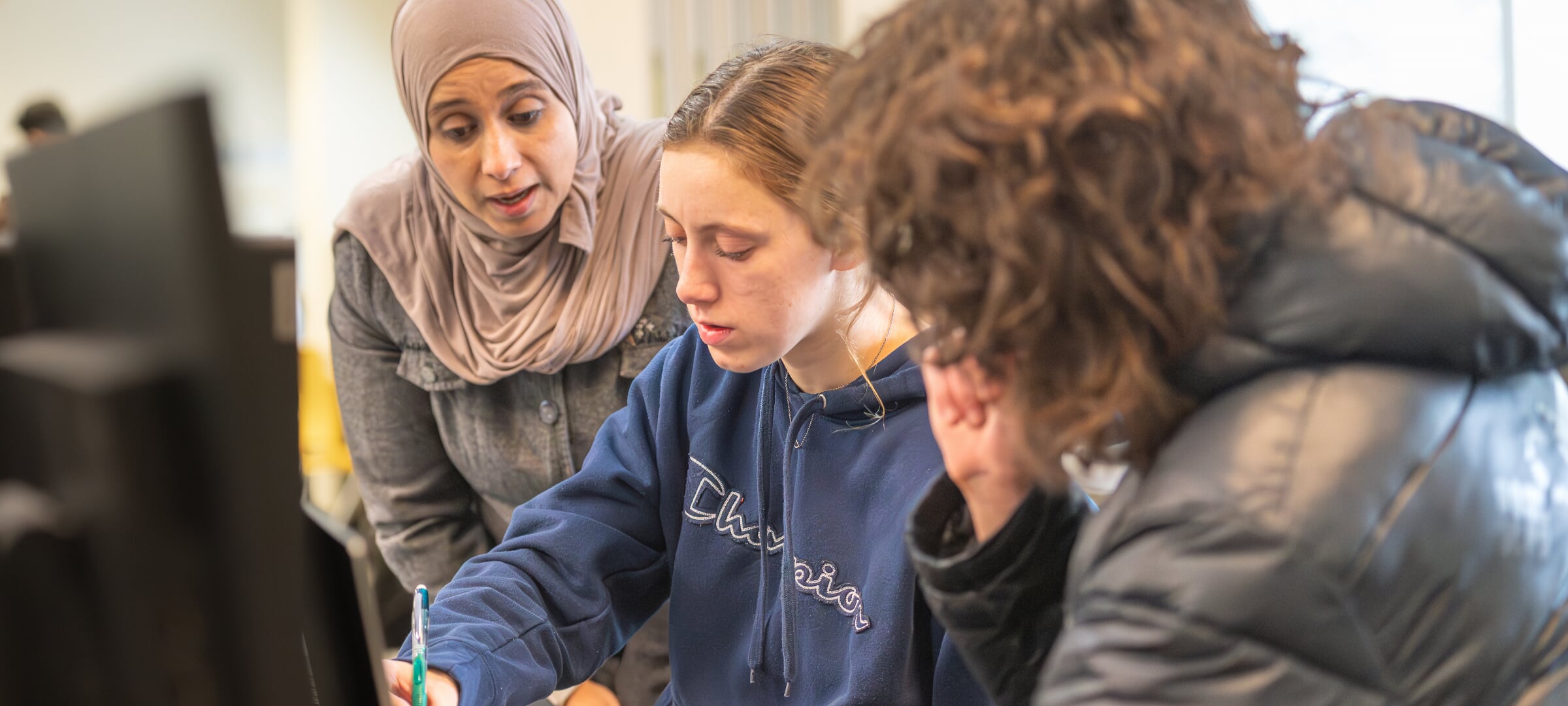 Two students work with one faculty on a project